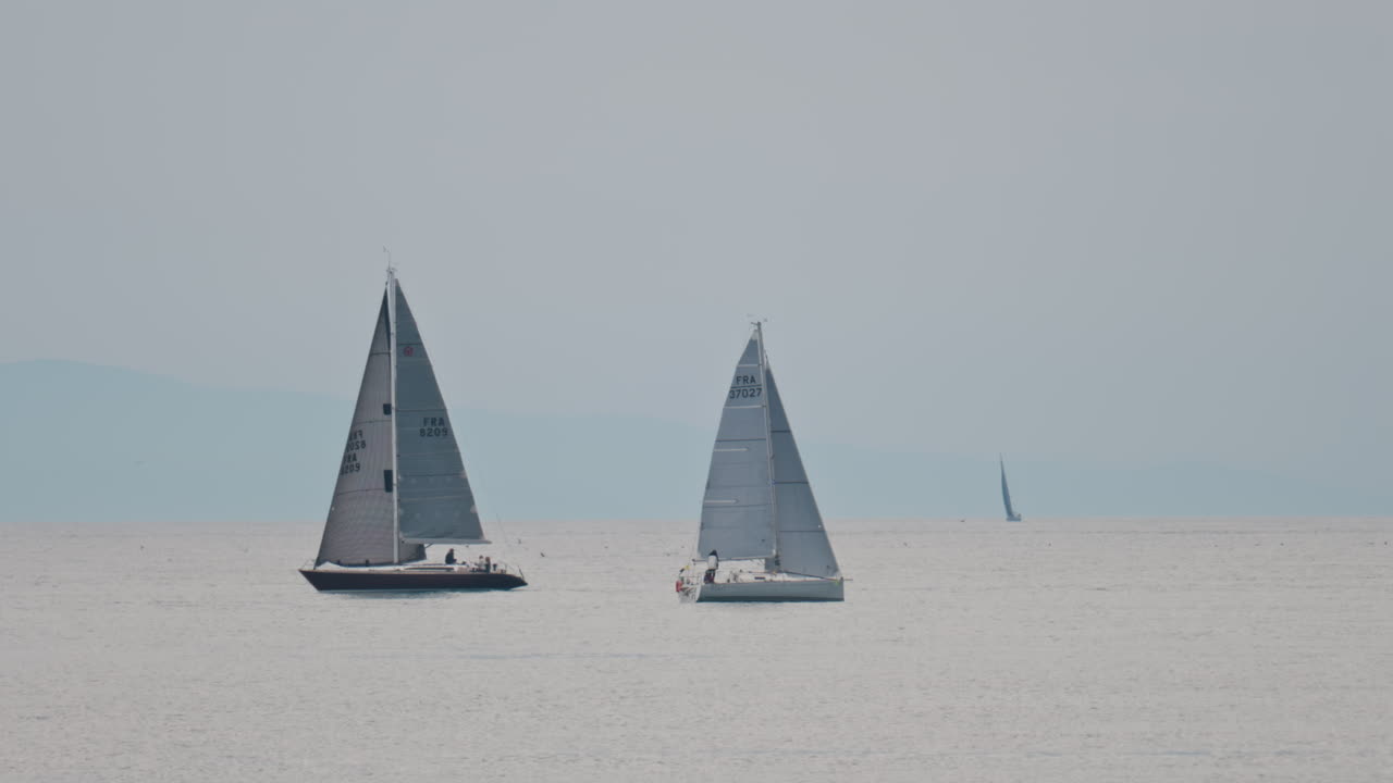 Antibes, France - May 6, 2025: Distant view of sailboats moving on the sea on a cloudy day