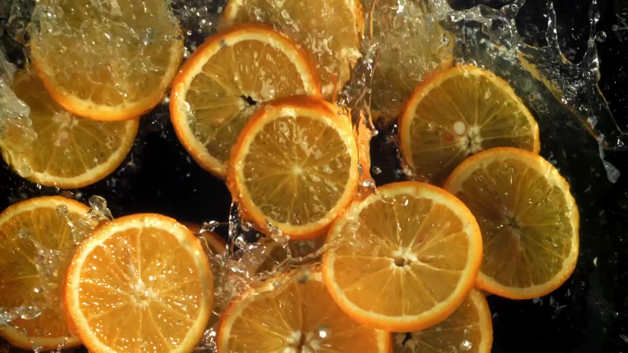 Câmera Super Lenta de Fatias Frescas de Laranja Caindo na Água.