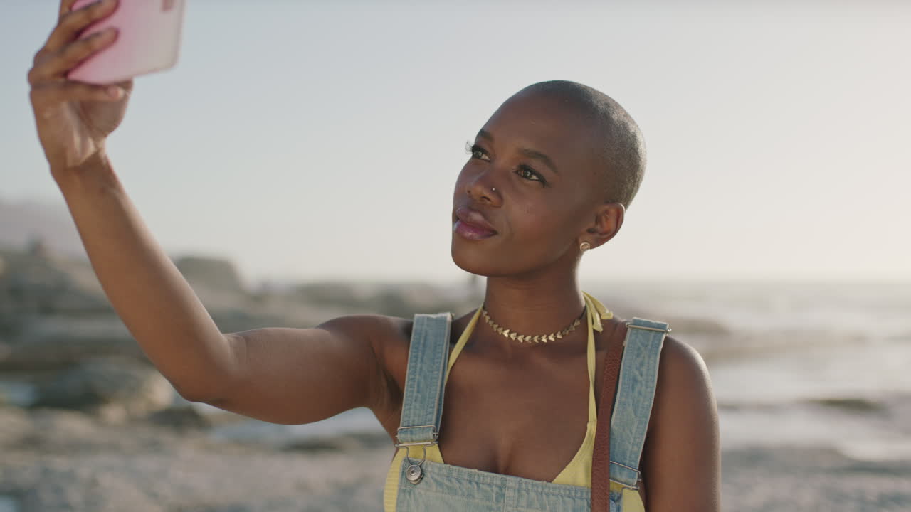retrato de uma atraente mulher afro-americana tirando uma selfie na praia