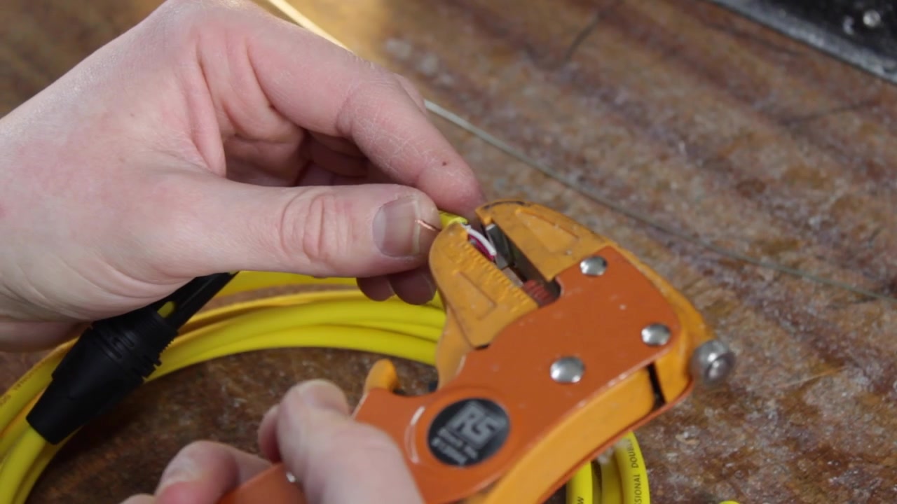 Lydskærmet mikrofonkabel, der afisoleres og forberedes til lodning. Professionel fremstilling af mikrofon-, guitar- og instrumentkabler.