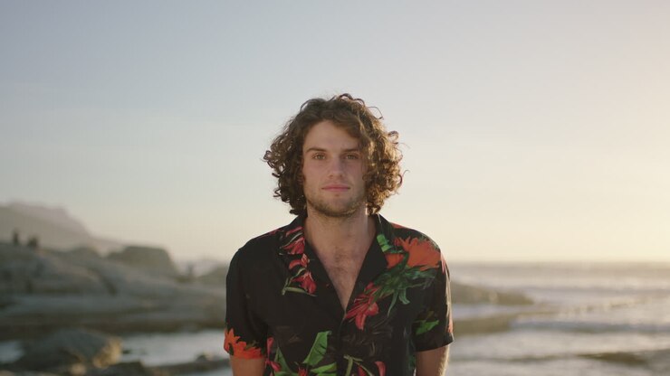 ritratto di un bell'uomo sulla spiaggia che fissa guardando indossando una camicia aloha