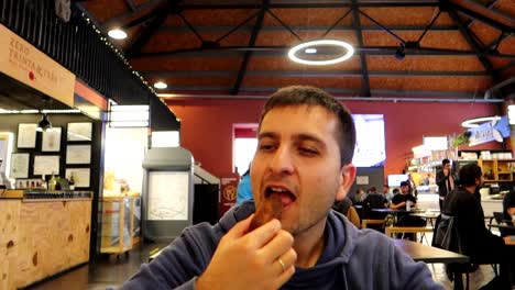 hombre comiendo deliciosa croqueta de bacalao en el mercado de beira mar, porto