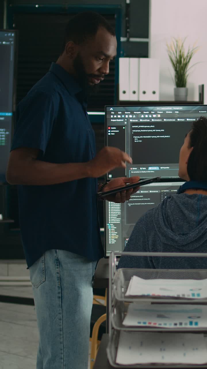 Vertical video: Software programmers talking about algorithms on big screen and tablet