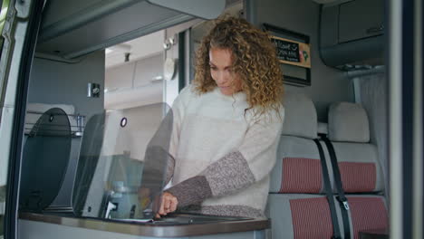 woman cooking camper van at morning close up. happy curly lady prepare breakfast