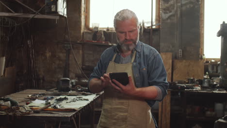 blacksmith working on digital tablet in smithy