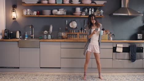 happy woman dancing in kitchen loop funny girl using smartphone having fun dance drinking coffee wearing pajamas at home silly morning routine