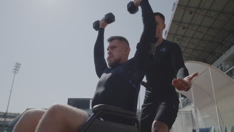 man in wheelchair working out with trainer
