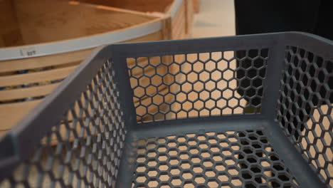 view of a lady in a black coat and black boots placing a loaf of bread into an empty shopping trolley. shot with a handheld camera, capturing the action from a detailed perspective in a grocery store