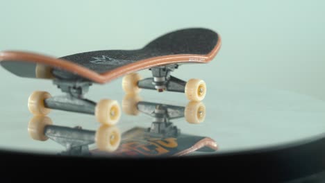 a detailed close-up shot of a mini skateboard, tiny white wheels, fingerboard on a 360 rotating stand, shiny mirror reflection, professional lighting, cinematic 4k video pan right