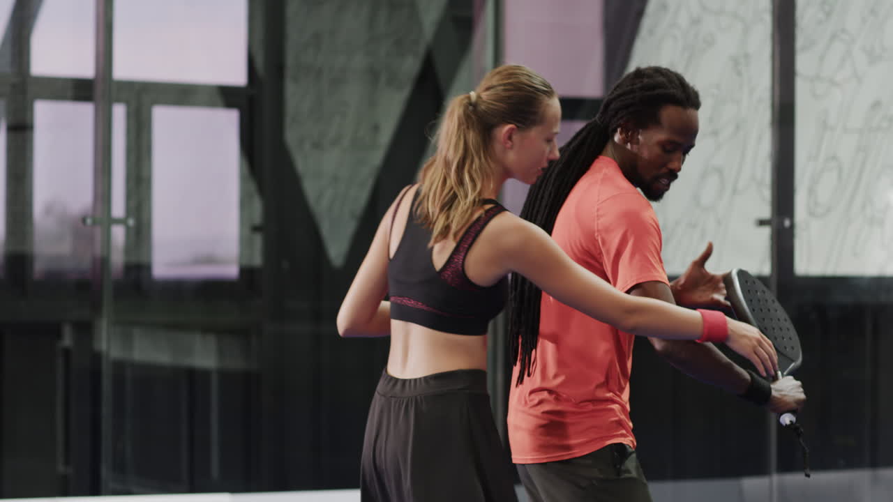 Diverse athletes practicing padel tennis techniques together on court, focused and engaged