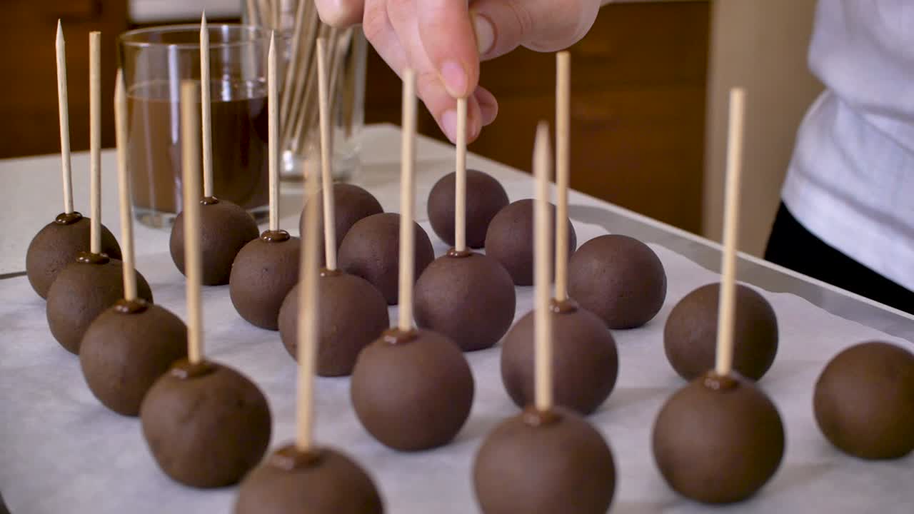 surtido de cakepops simples, poniendo palo de madera en bolas de chocolate