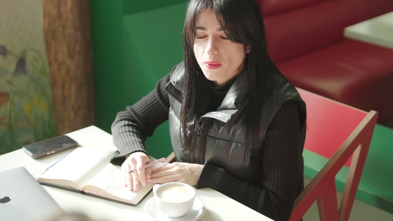 검은색 의상을 입은 전문적인 여성 관리자가 사무실을 걸어다니며 동료들과 상호 작용하며 문서와 노트북을 들고 리더십과 전문성을 보여주고 있습니다.