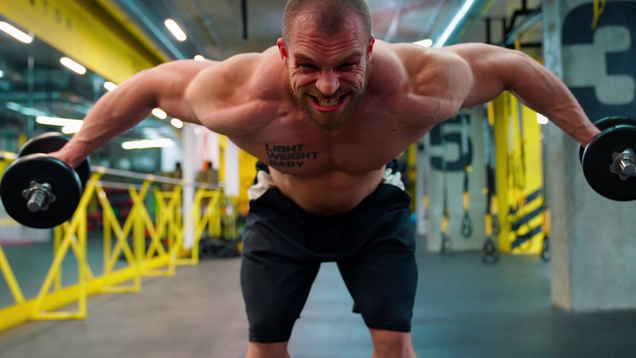 Uomo muscoloso che esegue alzate laterali con manubri in palestra