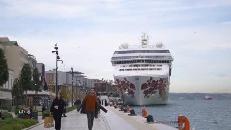 barco de crucero atracado en un puerto con personas caminando por la orilla