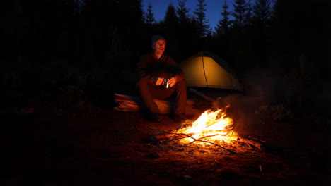 man camping by campfire at night