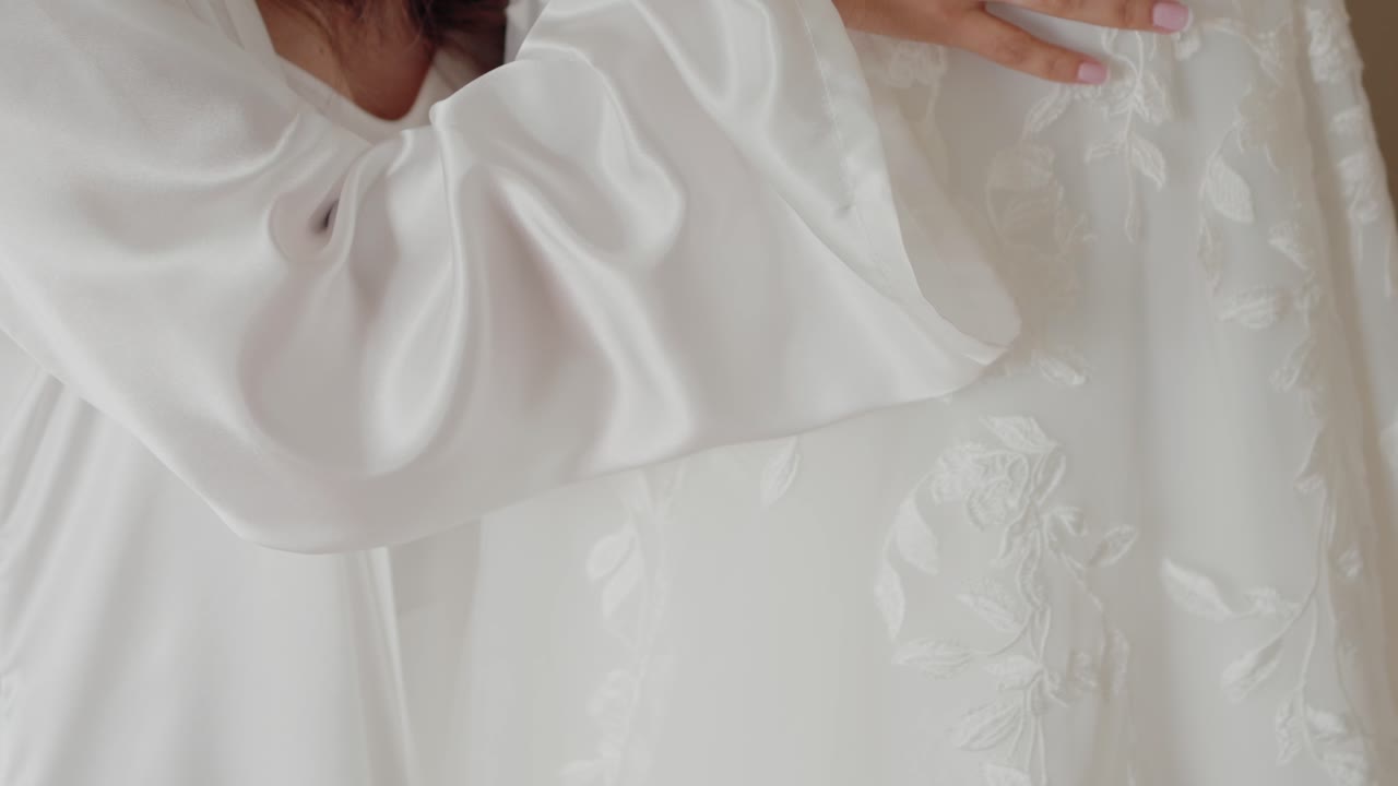 Bride touching her embroidered wedding dress, showcasing intricate floral details