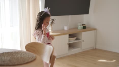 una joven baila alegremente en una sala de estar luminosa y acogedora. lleva un vestido rosado con un diseño de corazón, moviéndose juguetón en el espacio minimalista iluminado por el sol con decoración neutral y luz natural suave.