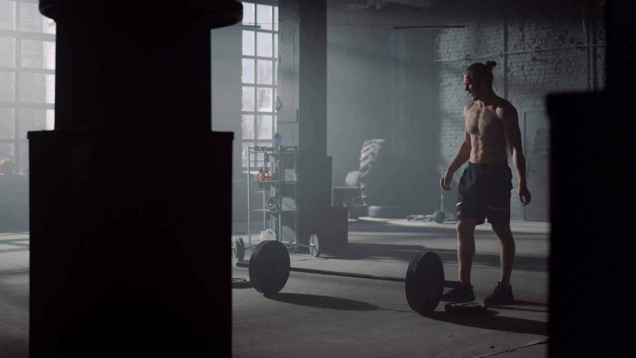 Young sportsman checking weights before lifting barbell in sports club