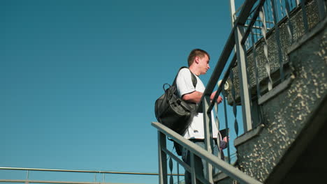 couple walking up outdoor staircase in casual attire, man engaging in cheerful conversation with friend, bright sunny day with modern railing design