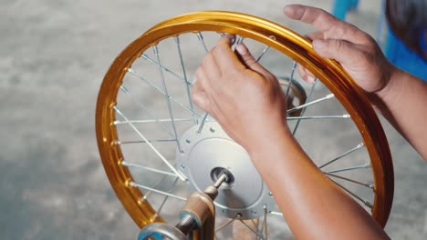 technician man working motorcycle wheel has spokes weave up on mechanic tool new steel wheel