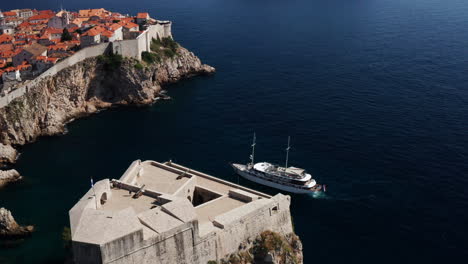 boat with tourists cruising at adriatic sea near walls of dubrovnik and lovrijenac in croatia