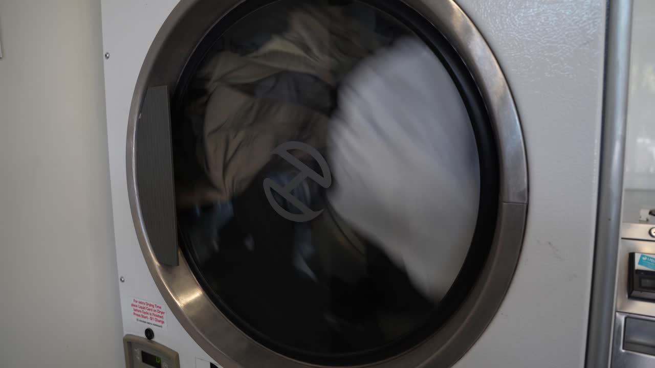 cargador lateral máquina secadora gira con la ropa cayendo y cayendo en la lavandería