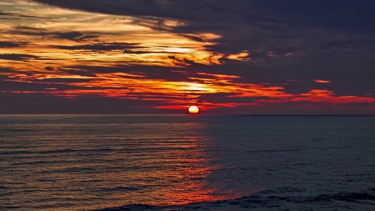A mesmerizing sunset over the ocean captured from a low-angle, creating a serene and vibrant scene