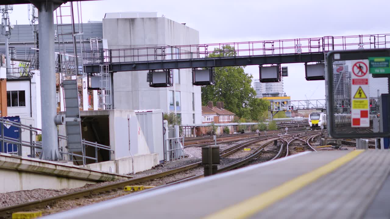 London Train Station with Locomotive Carrying Passengers Leaving Station Heading to Destination. Multiple Rails with Signal Lights Above