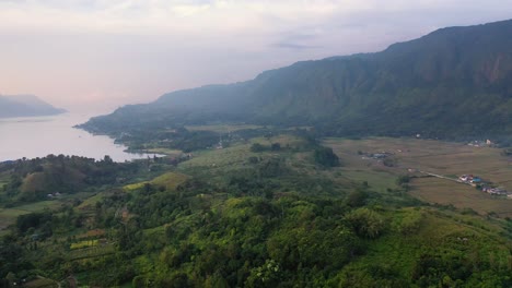 Aerial-view-of-plantations-and-fields-below-big-hills-on-Samosir-Island-in-Lake-Toba-in-North-Sumatra,-Indonesia