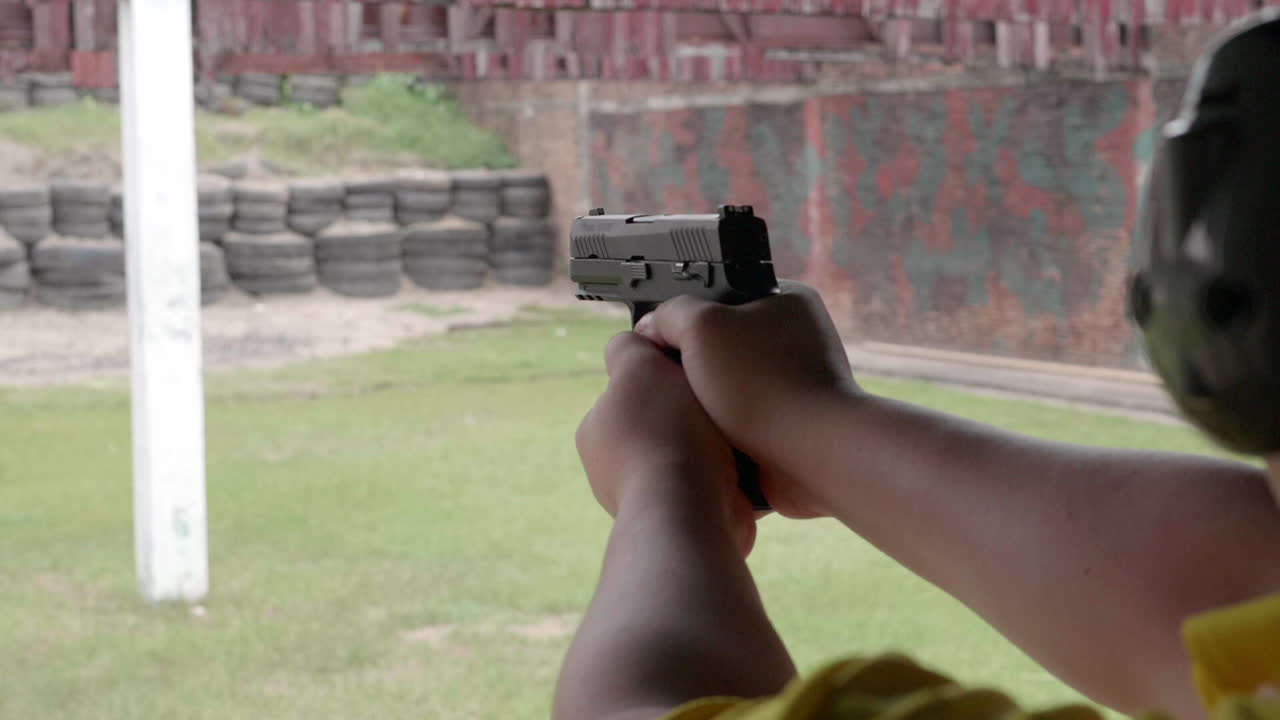 남자 손의 사격장에서 총을 발사하는 슬로우 모션 장면은 총을 단단히 잡고 방아쇠를 당깁니다