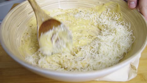 mezclando queso con salsa de ensalada césar dentro de un tazón de cocción profundo