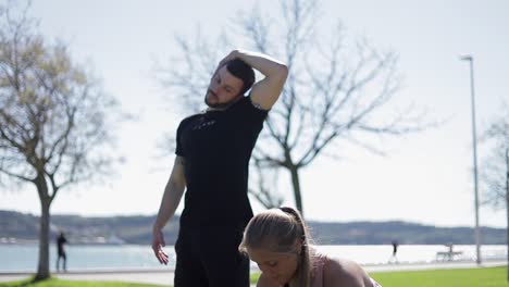 fröhliche menschen in sportkleidung wärmen sich im park auf.