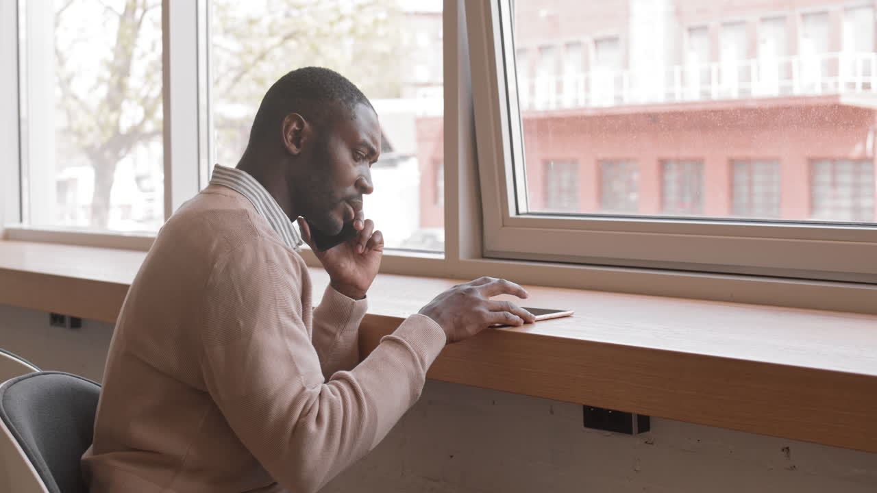 Afroamerikansk affärsman som pratar i telefon på ett kafé