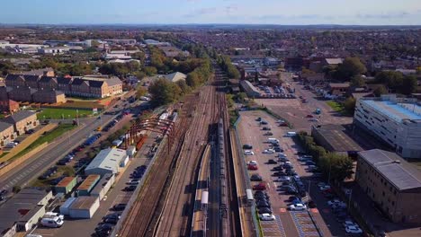 Drone-shot-of-a-train-leaving-Sittingbourne-station,-flying-forwards-and-panning-up