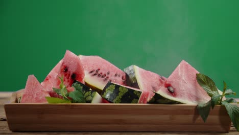 pieces of fresh watermelon on wooden tray with cool steam.