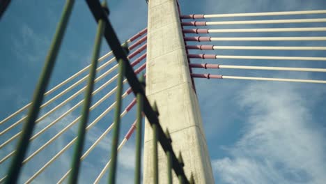 Concrete-suspension-cable-bridge-through-rusty-fences-with-cloudy-sky-at-sunrise