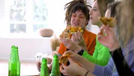 vista laterale delle amiche che parlano, ridono e mangiano pizza durante una festa diurna