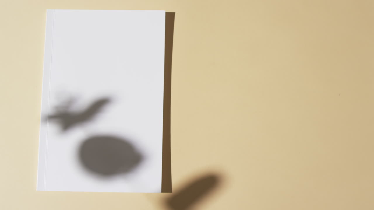 노란색 배경에 빈  페이지와 복사 공간을 가진 책 위에 식물의 그림자의 비디오