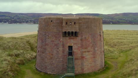 smooth aerial pullback showcasing the martello tower at magilligan point, highlighting the entrance of the tower