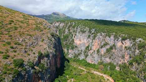 Aerial-drone-backward-moving-shot-over-tourists-sunbathing-along-Gjipe-Beach-with-canyon-in-the-background-in-Dhermi,-Albania-on-a-bright-sunny-day