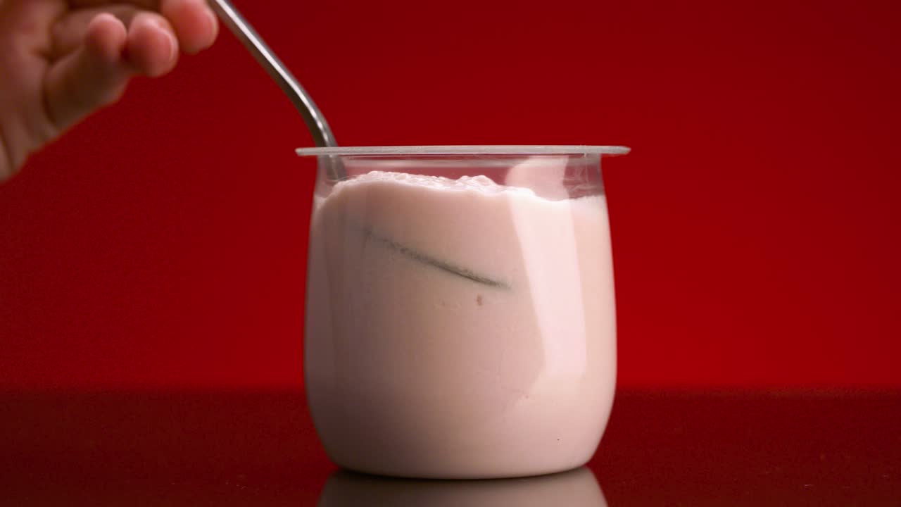 손으로 으로 분홍색 요구르트를 먹는 것