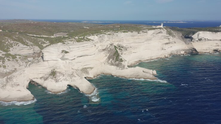 Bonifacio, Corsica: foto aerea con drone di costa, scogliere, faro, aspro paesaggio calcareo e iconica isola francese sul Mar Mediterraneo turchese