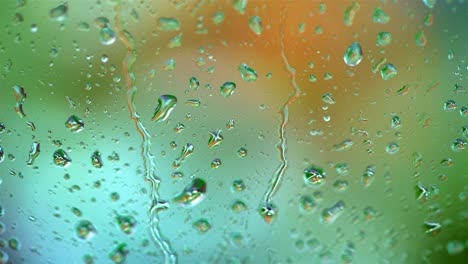 raindrops on blur colorful background. large drops flowing on glass window slowly in rainy weather. close-up.