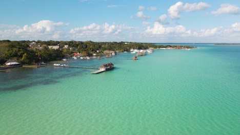 baja acercándose a una villa de agua tomada por un dron de la hermosa laguna de siete colores en bacalar, méxico en 4k