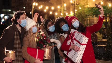 portrait of happy multiethnic friends making a selfie and holding presents on the street while it¬¥s snowing in christmas