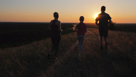 a young child with a couple jogging outdoors in scenic location on the sunset