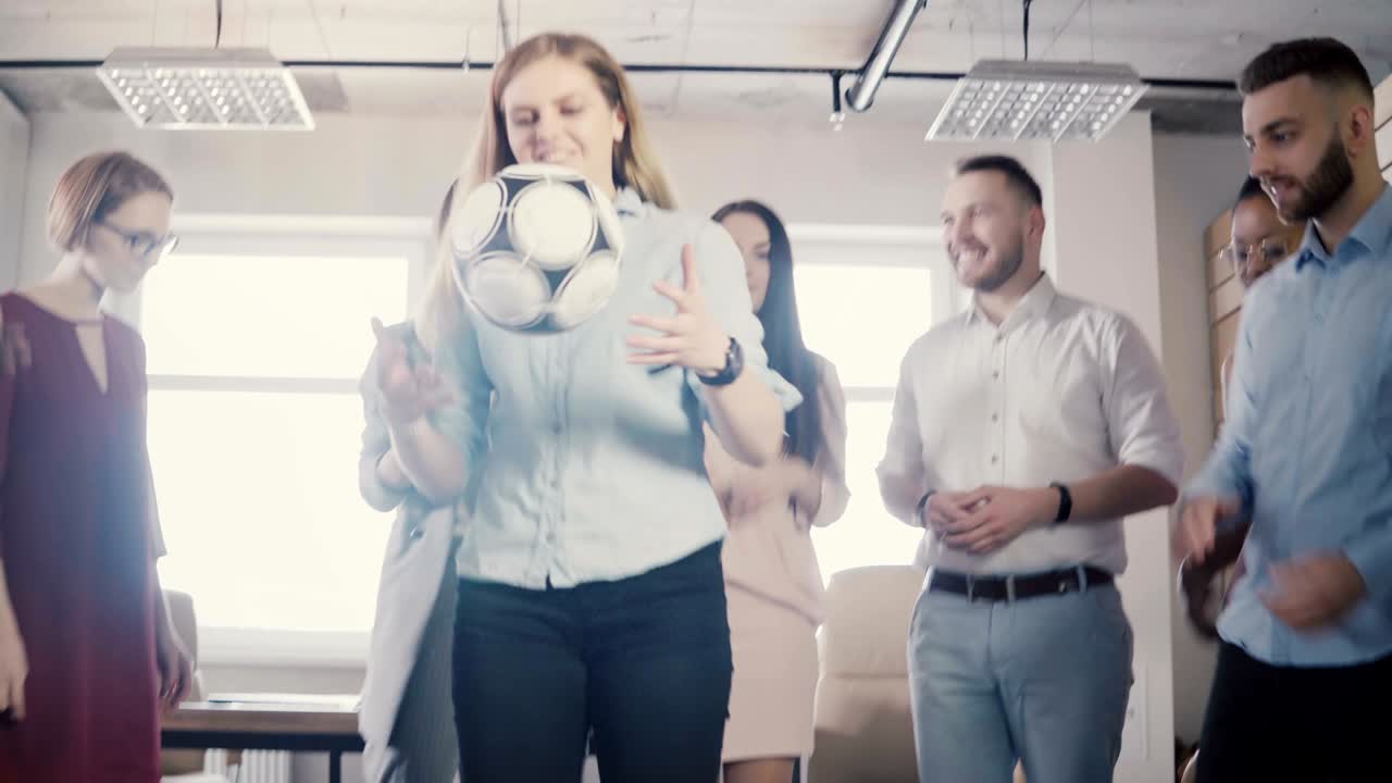 empleados felices de la oficina llevan a cabo una actividad física. jóvenes colegas multiétnicos celebrando, jugando con la pelota de fútbol 4k