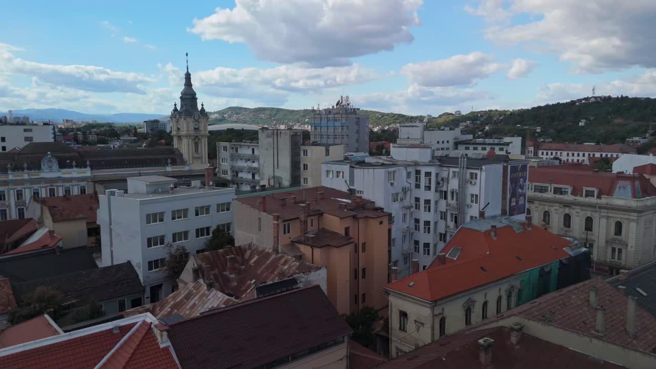 Cityscape with red roofs, cloudy sky, and distant mountains
