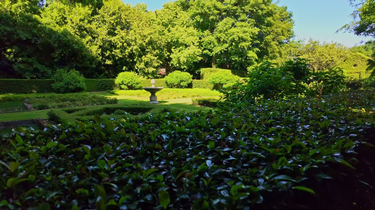 Wide view of beautiful lush garden with trimmed hedges and symmetrical flower beds at Upper Brittany Botanical Park, Le Chatellier, France.
