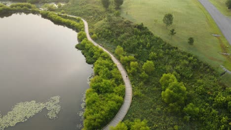 female jogging a path around a fishing pond during sunrise